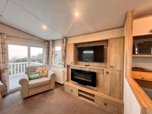 a living room with a television and a couch and a chair at Swanage Luxury Caravan - Stunning sea views, Large decking area, Free EE WIFI, Sleeps 6, Pet Friendly on Swanage Bay View Holiday Park in Swanage