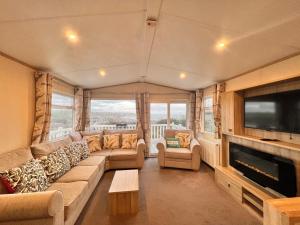 a living room with a large couch and a television at Swanage Luxury Caravan - Stunning sea views, Large decking area, Free EE WIFI, Sleeps 6, Pet Friendly on Swanage Bay View Holiday Park in Swanage