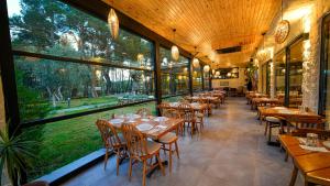 a restaurant with wooden tables and chairs and large windows at Garrya Romo Hotel in Urla