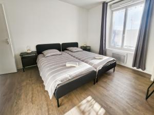 a large bed in a room with two windows at Appartement Confortable à Coulommiers avec Jardin in Coulommiers