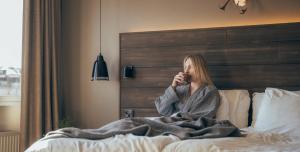 a woman sitting on a bed talking on a cell phone at Lapland Hotels Kuopio in Kuopio
