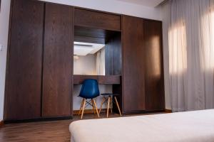 a bedroom with a large wooden partition with a blue chair at Fallsway Palms in Lusaka