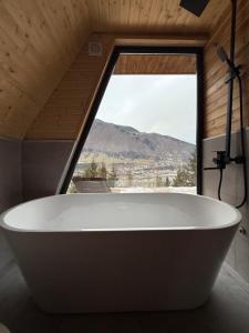 a bath tub in a bathroom with a large window at "Panorama" Kakhri in Mestia +87 photos