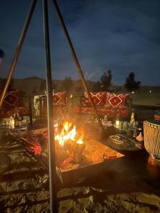 a fire pit on a beach at night at Desert Luxury Camp Merzouga in Merzouga