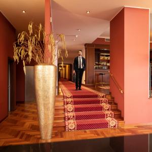 a man in a suit walking down a staircase with a vase at Hotel Maxim in Peschiera Borromeo +36 photos