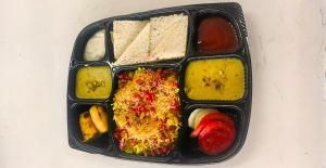 a black plastic container filled with different types of food at Solasta Stays and Banquet - Wakad in Pune
