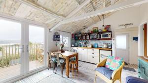 a kitchen with a table and chairs and a balcony at E41 Silver Mist, Riviere Towans in Hayle