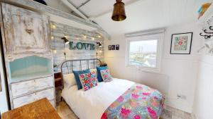 a bedroom with a bed with a love sign on the wall at E41 Silver Mist, Riviere Towans in Hayle