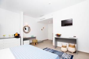 a bedroom with a bed and a desk and a television at Lindos Portes Blue in Lindos