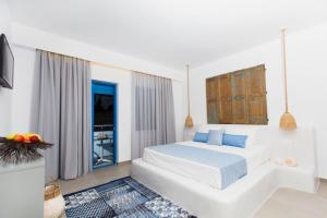 a white bedroom with a large bed with blue pillows at Lindos Portes Blue in Lindos +9 photos