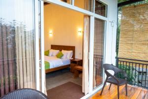 a room with a bed and a balcony with a window at AnuBi Nest Ella in Ella