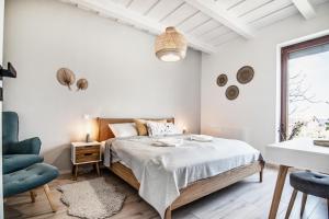 a white bedroom with a bed and a blue chair at Bandi Weekend House in Somlójenő