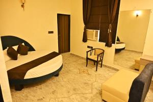 a bedroom with a bed and a chair in a room at Hotel Rajmahal Regency in Faridabad