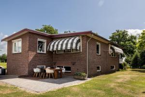 a brick house with a table and chairs on a patio at Bij nr 5 Teuge in Terwolde