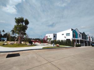 a playground in front of a white building with a house at Dolce Home suratthani in Suratthani