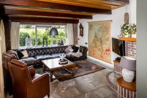 a living room with a leather couch and a table at Bij nr 5 Teuge in Terwolde
