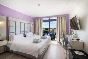 a bedroom with a large bed and a desk with a computer at Hotel Santa Eulália Bay - Adults Only in Albufeira