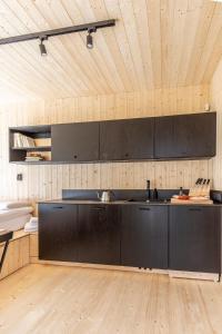 a kitchen with black cabinets and a wooden floor at Hidden Base - romantyczna leśna kryjówka in Smolarnia