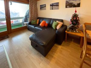 a living room with a black leather couch and a christmas tree at Apartment Hauts de Nendaz BI3 by Interhome in Nendaz