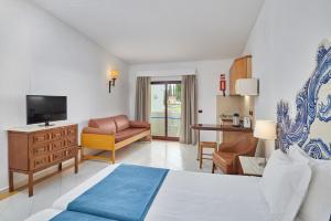 a bedroom with a bed and a living room at Hotel Apartamento Do Golfe in Vilamoura