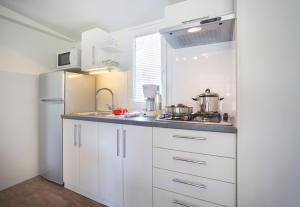a kitchen with white cabinets and a refrigerator at Maistra Camping Polari Mobile homes in Rovinj