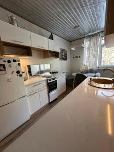 a kitchen with white cabinets and a white refrigerator at Apartment with sauna and fireplace in Viitna