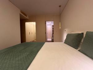 a bedroom with a large white bed with green sheets at Music Apartment II in Bicas