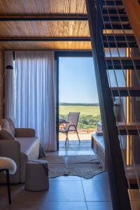 a living room with a couch and a chair and a window at Cabanas Horizonte Cambará Nature in Cambará