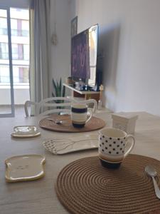 a table with two cups and plates and a tv at Departamento céntrico Crespo in Santa Fe
