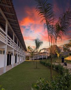 a palm tree in front of a building with a sunset at Lagamar Hotel Varginha in Varginha