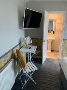a living room with a table and a tv at Neptunes Rest Guest Hotel in Stranraer