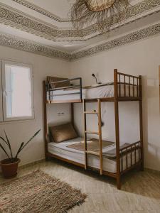 two bunk beds in a room with a ceiling at Dania Surf House in Mirleft