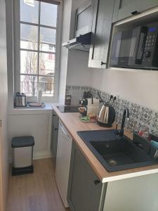 a small kitchen with a sink and a microwave at Le 16 Place de l'Abbatiale in Évron +2 photos
