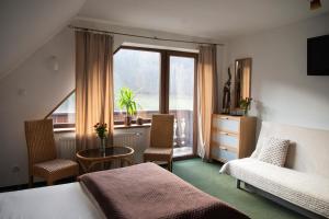 a bedroom with a bed and a table and a window at Willa Pod Dobrym Humorem in Miedzygorze