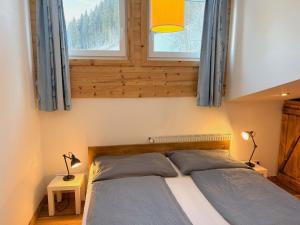 a bedroom with a bed and two windows at Apartment Daniel by Interhome in Hollersbach im Pinzgau