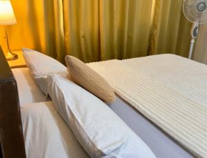 a bed with two pillows on it with a fan at Hannah’s Morning Sun - Studio Room in Manila +24 photos