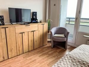a bedroom with a tv on a wooden cabinet with a chair at Apartment Ostsee-Residenz - DMP173 by Interhome in Damp