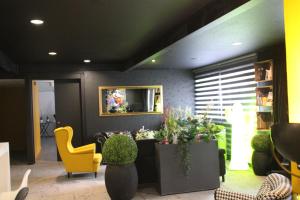 a lobby with a yellow chair and some plants at The Originals City, Hôtel Le Louisiane, Belfort Sud in Andelnans