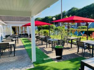 a group of tables and chairs with red umbrellas at The Originals City, Hôtel Le Louisiane, Belfort Sud in Andelnans