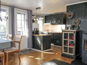 a kitchen with darkcolored cabinets and a table and chairs at Holiday Home Evabu by Interhome in Øyuvstad