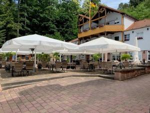 a patio with tables and chairs under white umbrellas at Schlosshotel Landstuhl in Landstuhl
