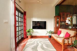 a living room with a couch and a tv at House StoneHaven in Kaniyāmbetta