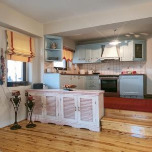 a kitchen with white cabinets and a wooden floor at Amadrias Villa Florina in Florina