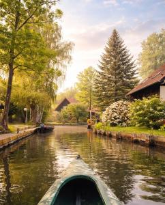 a boat on a river with trees and houses at Spreewald Spreemilia Gurkenbude in Lübbenau