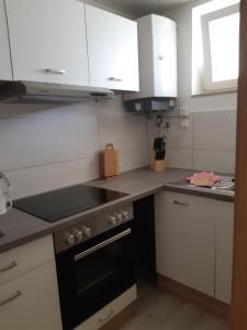 a kitchen with white cabinets and a black stove top oven at Schönes, modernes Appartement mit Balkon und Indoorpool in Oberteuringen