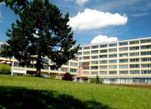 a large white building with a tree in front of it at Schönes, modernes Appartement mit Balkon und Indoorpool in Oberteuringen