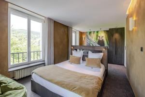 a bedroom with a large bed with a large window at Les Loges Du Parc in Gérardmer