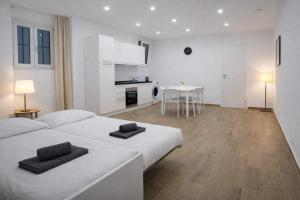 a white bedroom with a large bed and a kitchen at Maison TRENCA - fully equiped apartment in Menton