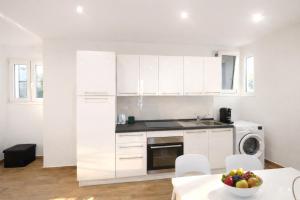 a kitchen with white cabinets and a table with a bowl of fruit at Maison TRENCA - fully equiped apartment in Menton