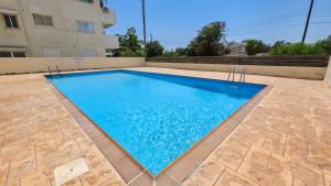 a swimming pool with blue water in front of a building at Sunset Poolside Apartment with Pool facility in Larnaca